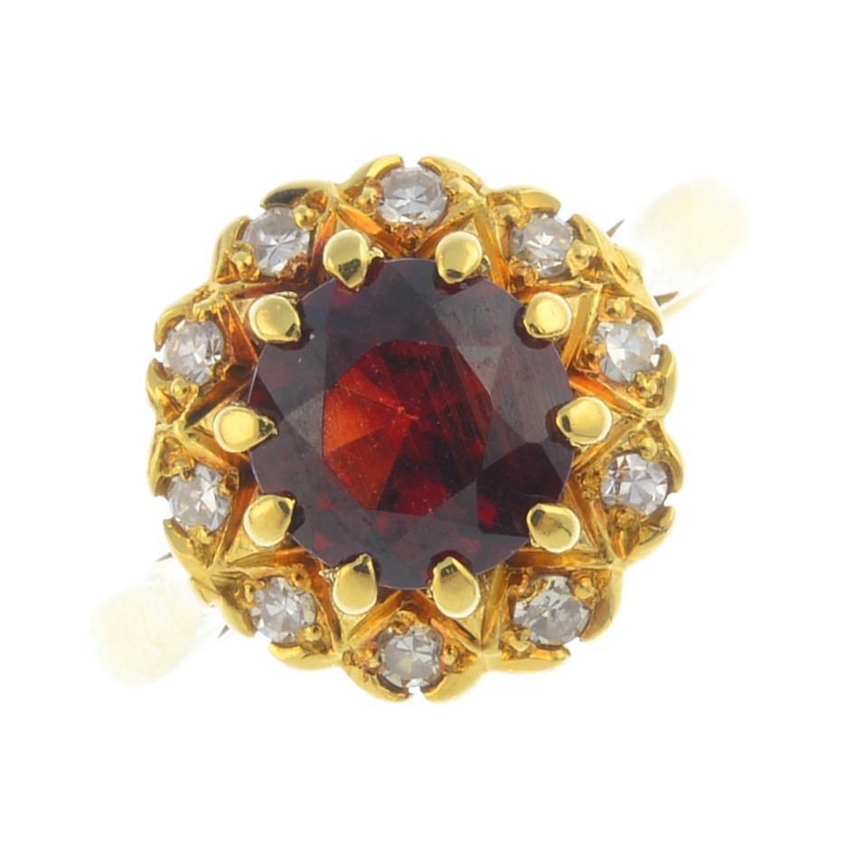 An 18ct gold garnet and diamond cluster ring. The circular-shape garnet, within a single-cut diamond