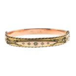 An Edwardian 9ct gold diamond bangle. The star-set diamond tapered panel, with cannetille, rope-