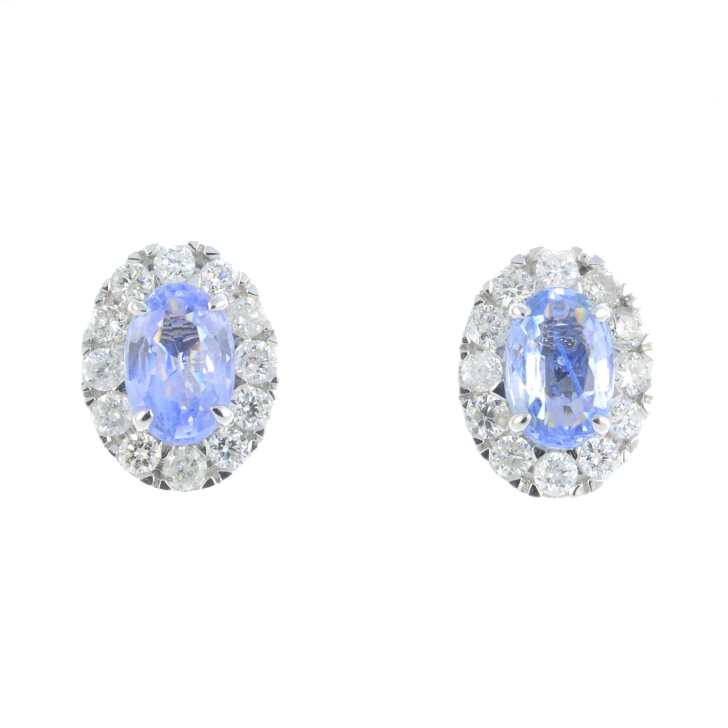 A pair of sapphire and diamond cluster earrings. Each designed as an oval-shape sapphire, within a