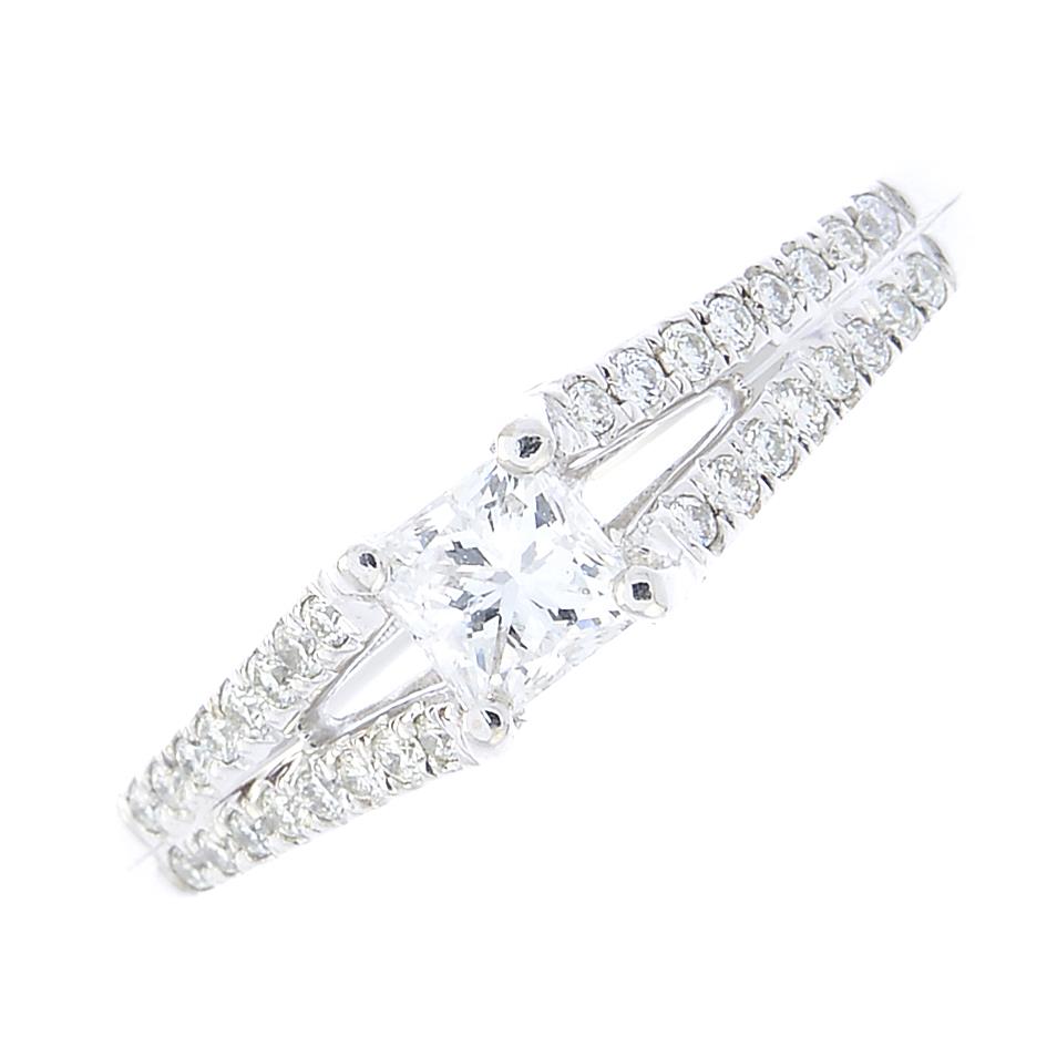 An 18ct gold diamond ring. The square-shape diamond, with brilliant-cut diamond chevron shoulders.