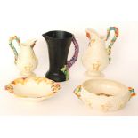 Four pieces of 1930s Clarice Cliff comprising two graduated water jugs with high arch handle,