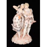 A late 19th Century Volkstedt bisque figural group modelled as a young lady and gentleman in