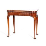 A George II mahogany fold-over tea table, with husk carved knees to the tapered legs over pad feet,