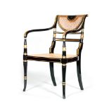 A Regency ebonised and parcel gilt elbow chair with cane seat and back on turned splayed legs to