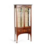 An Edwardian Art Nouveau inlaid mahogany display cabinet enclosed by a pair of coloured leaded