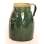 An early 20th Century Jugenstijl cream jug glazed in green with an applied four piece motif,