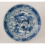 A late 19th Century Chinese blue and white charger decorated with Fo dogs amidst clouds within a