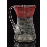 A late 19th Century glass tankard of waisted form with applied handle and cranberry threading to