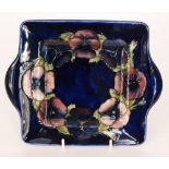 A Moorcroft square dish with moulded twin handles decorated in the Pansy pattern with tubelined