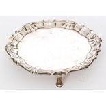 A George II hallmarked silver waiter of plain circular outline with shell and scroll border and
