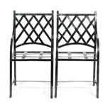A pair of steel garden armchairs with lattice woven backs and strapwork seats.
