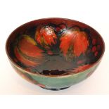 A large William Moorcroft footed bowl decorated in the Flambe Leaf and Berry pattern with a band of