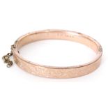 A Victorian 9ct rose gold hinged bangle with foliate decoration and engraved I.S.
