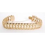 A Continental 18ct pierced and textured flexible bracelet terminating in tongue and box clasp,