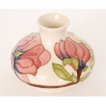 A Moorcroft Pottery vase of compressed form decorated in the Magnolia pattern with pink tubelined