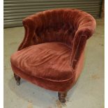 A Victorian tub chair, upholstered in deep red button down velvet above turned mahogany front legs.