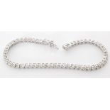 An 18ct white gold diamond tennis bracelet comprising fifty seven claw set brilliant cut stones,