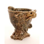 A novelty stoneware egg cup modelled as a stylised eagle head with protruding eyes and feather