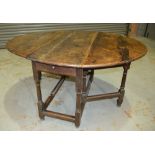 An 18th Century oak gateleg dining table on turned gun barrel legs united by rail stretchers,