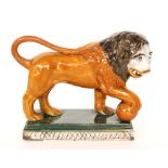 A 19th Century Staffordshire pearlware model of a lion with his front paw on a ball, unmarked,