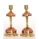 A pair of Arts and Crafts brass candlesticks with copper domed details below plain cylindrical