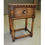 A small 17th Century style oak side table with a florette carved drawer on castellated legs united