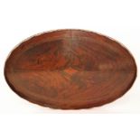 A mahogany tray of oval form with a pie crust style wavy edge and inlaid detail to the centre,