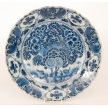 A late 19th Century Delft tin glaze plate decorated in blue and white with a large spray of flowers