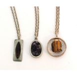 Three Danish pewter pendants by Jorgen Jensen to include a tiger's eye mounted pendant,