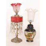 A Victorian drop lustre oil lamp with ruby glass reservoir on plated rococco style base,