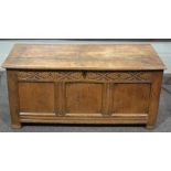 An 18th Century oak coffer, the plank top over a leaf carved frieze and panelled front,