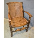 A 20th Century stained beech bergere armchair with barleytwist capitals over a stretcher frame.