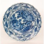A late 19th Century Delft tin glaze plate decorated in blue and white with a large spray of flowers