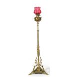 A Victorian brass standard lamp with pierced column on scroll cast base with ruby moulded shade,