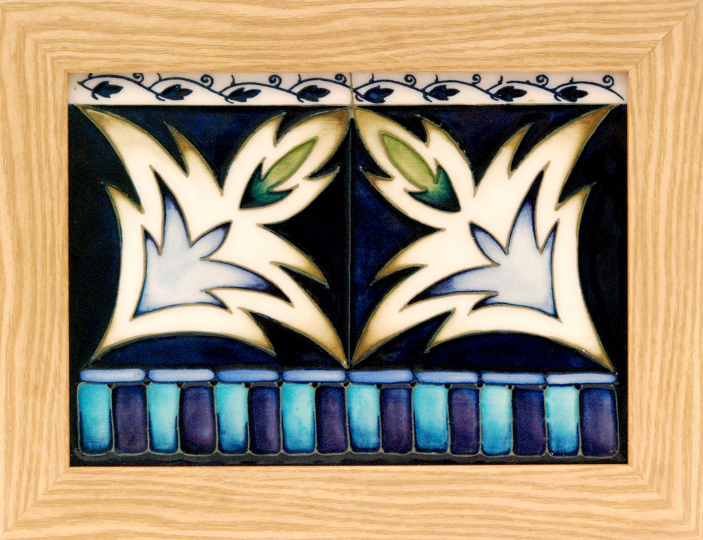A Moorcroft Pottery framed rectangular panel decorated with two tubelined stylised leaves within