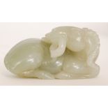 A Chinese pale celadon jade carving of a recumbent goat or ram with its head turned back holding a