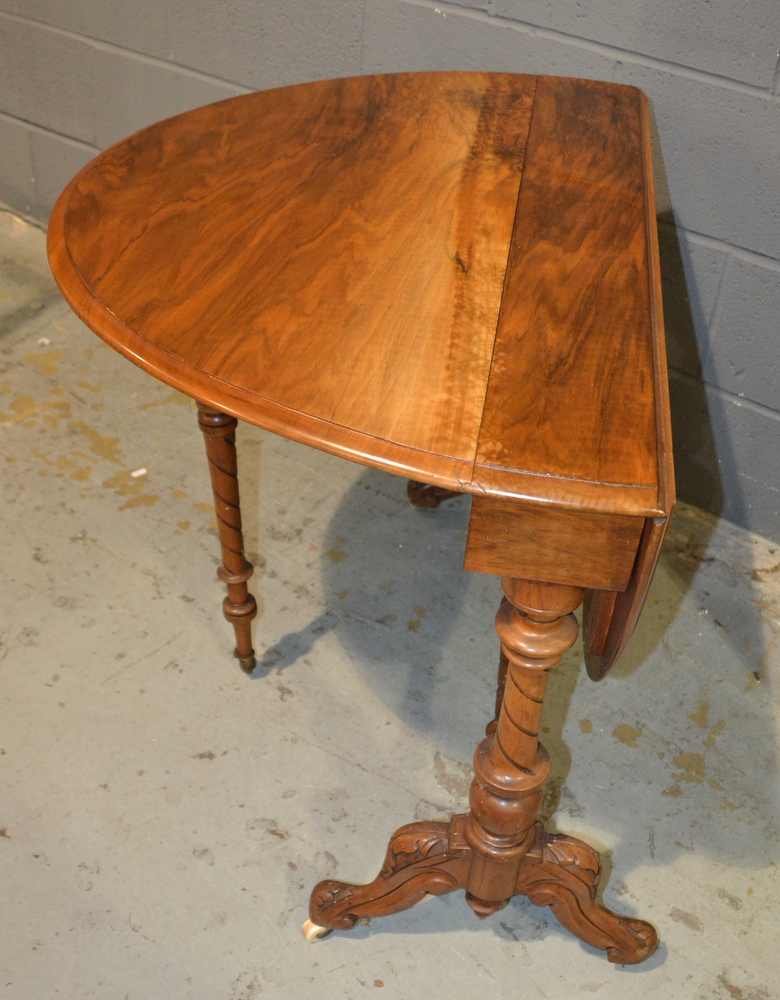 A Victorian oval walnut drop flap Sutherland table on turned scroll ends united by a turned