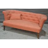A Victorian three seat sofa, upholstered in pink buttoned damask, on turned legs to the front,