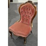 A Victorian carved walnut framed easy chair upholsterd in pale pink buittoned back plush on