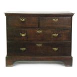 A George III oak straight front chest of two short and two long drawers fitted with brass drop