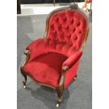 A Victorian carved mahogany framed easy chair with scroll arms upholstered in deep buttoned back