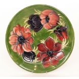 A Moorcroft Pottery shallow plate decorated in the Anemone pattern with tubelined flowers against a