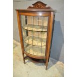 An Edwardian mahogany bow front display cabinet enclosed by a coloured leaded light glazed door on