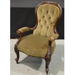 A Victorian carved walnut easy chair, upholstered in buttoned down green upholstery,