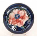 A Moorcroft roll rim bowl decorated in the Anemone pattern with a central flower against a blue