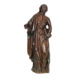 A late 18th Century carved oak figure of a standing robed apostle holding a book in his left hand,