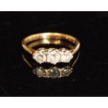 An 18ct three stone diamond ring, central round brilliant cut stone with smaller stone beside,