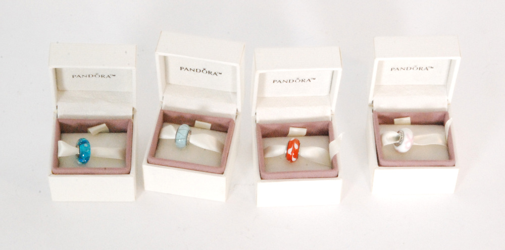 Four boxed charms stamped Pandora and ALE, examples to include pink ribbon, orange murano glass,