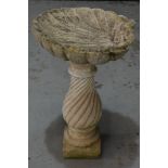 A contemporary garden bird bath of scallop shell form above a wrythen baluster shaped pedestal,