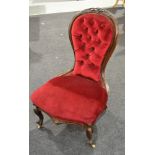 A Victorian carved walnut balloon back easy chair upholstered in buttoned crimson plush on cabriole